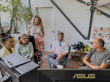 Fünf Personen befinden sich in einem Büro und blicken alle auf einen Bildschirm.