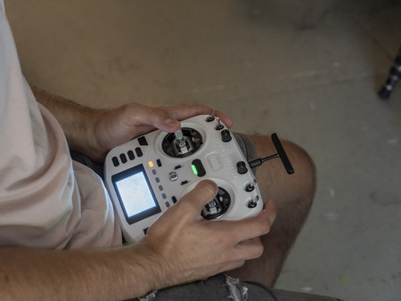 Eine Person hält einen modernen Fernsteuerungscontroller mit beiden Händen. Der Controller hat zwei Joysticks und ein Display. 