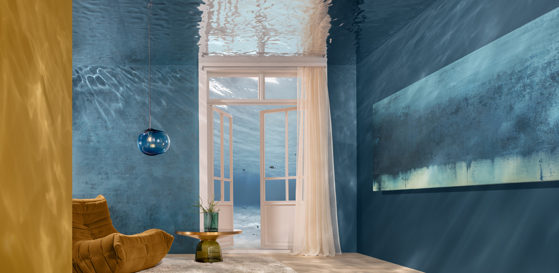 Ein Raum mit blauen Wänden. Ein offenes Fenster lässt Licht herein. In der Ecke steht ein beiger, bequemer Sessel und ein runder Tisch mit einer Pflanze.
